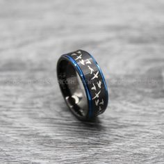 a black and blue wedding ring with white skulls on it, is sitting on a wooden surface