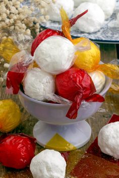 a bowl filled with marshmallows on top of a table next to other candies