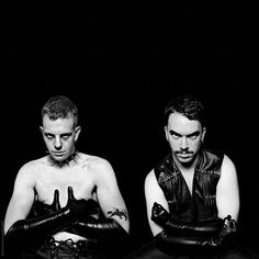 two men in leather gloves sitting down with their hands on their hipss and looking at the camera