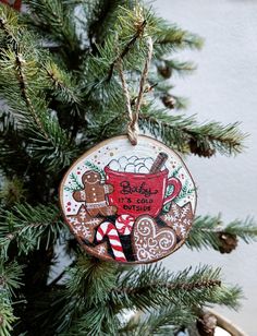 a christmas ornament hanging from a tree with gingerbreads and hot chocolate