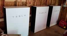 three tesla power panels in a garage with the word tesla printed on one of them