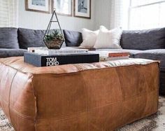 a living room with a couch, ottoman and books on the coffee table in front of it