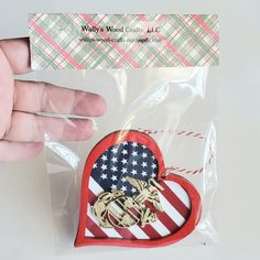 a person holding up a heart shaped brooch with an american flag pattern on it