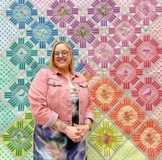 a woman standing in front of a colorful quilt