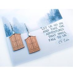 two wooden doors are hanging from earrings on a card