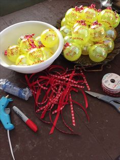 a bowl of yellow balloons sitting on top of a table next to scissors and tape