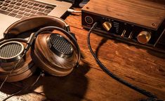 headphones sitting on top of a wooden table next to a laptop and stereo equipment