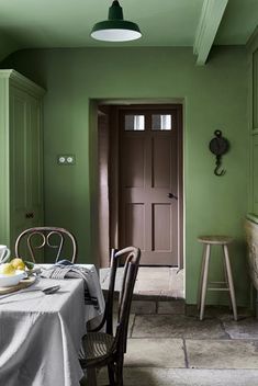 a dining room with green walls and chairs