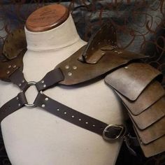 a white mannequin with leather armor on it's chest and shoulder straps