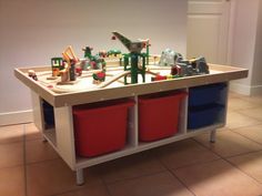 a child's play table with toy cars and toys in bins on the floor