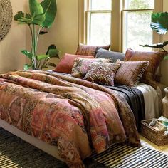 a large bed sitting next to two windows in a room with plants on the wall