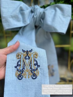 a person holding up a blue and gold monogrammed napkin with the letter m on it