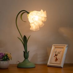 a lamp that is on top of a table next to a vase with flowers in it