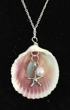 a shell with a starfish charm hanging from it's side on a chain