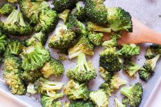 broccoli florets on a baking sheet with a wooden spoon