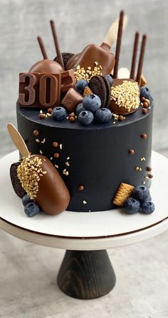 a chocolate cake decorated with blueberries, raspberries and gold sprinkles