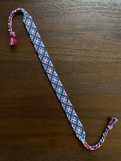 a blue and red tie on a wooden table with a tassel hanging from it's end