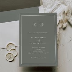 the wedding stationery is laid out on top of an envelope and two wax stampers