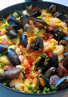 a pan filled with seafood and rice on top of a table