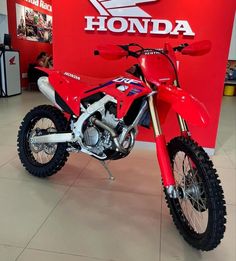 a red motorcycle parked in front of a honda sign