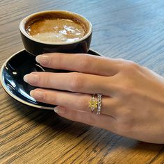 a woman's hand holding onto a cup of coffee on top of a saucer