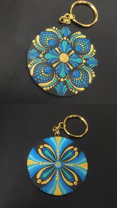 two blue and gold circular key chains on a black surface, one with an ornate design