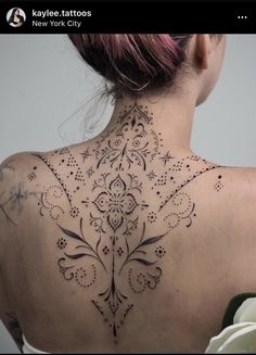 the back of a woman's neck is covered in intricate designs and stars on it