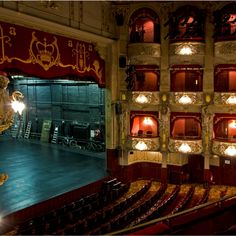 an empty theatre with red curtains and lights on the stage is lit by spotlights