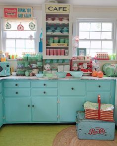 an old fashioned kitchen with blue cabinets and green flooring, including a vintage coke machine