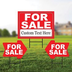 two red for sale signs sitting in the grass