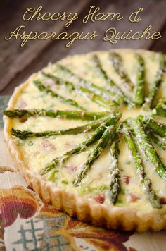 a quiche with asparagus and cheese is shown on a floral tablecloth