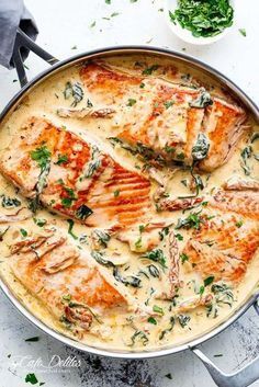 a pan filled with food on top of a white table next to silver spoons