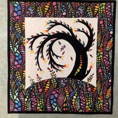 a quilted wall hanging with an abstract tree design