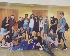 a group of young people posing for a photo in an empty room with wooden doors