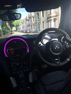 the interior of a small car with its dashboard lights on and steering wheel illuminated in pink