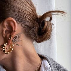 a woman wearing gold earrings and a white shirt is looking out the window with her back to the camera