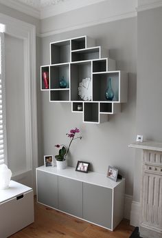 a living room filled with furniture and a white shelf next to a window on top of a hard wood floor