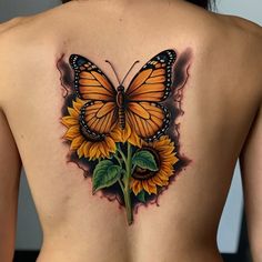 a woman's back with a butterfly and sunflower tattoo on her left side