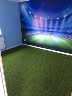 an empty room with green carpeting and a large wall mural in the corner that has a soccer field on it