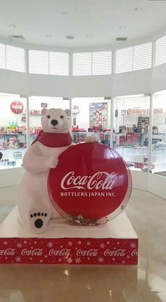 a large coca - cola sign in the shape of a polar bear holding a red ball