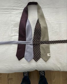 three ties laid out on top of a bed with one tied up and the other untied