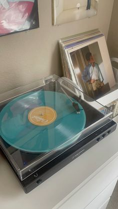 a record player sitting on top of a white table next to pictures and other items