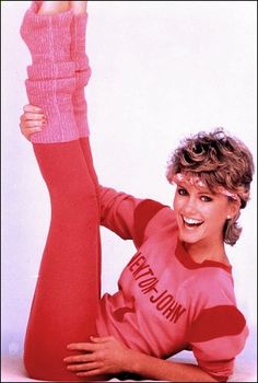 a woman in red shirt laying on the ground with her legs up and hands behind her head