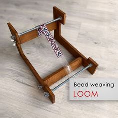 a wooden loom is sitting on the floor next to a sign that says bead weaving loom