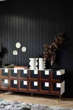 a living room with black walls and white vases on top of the sideboard