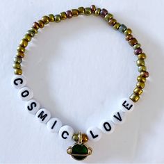 a bracelet with the word cosmic love written on it and a green beaded charm