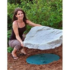 a woman kneeling down next to a large rock