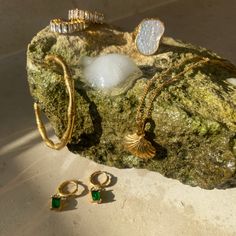 an assortment of jewelry sitting on top of a rock next to a pair of earrings