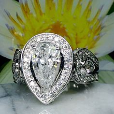 a close up of a diamond ring on a marble surface with a flower in the background