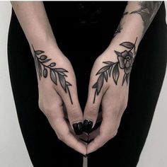 two hands with tattoos on them holding something in the shape of a heart and flowers